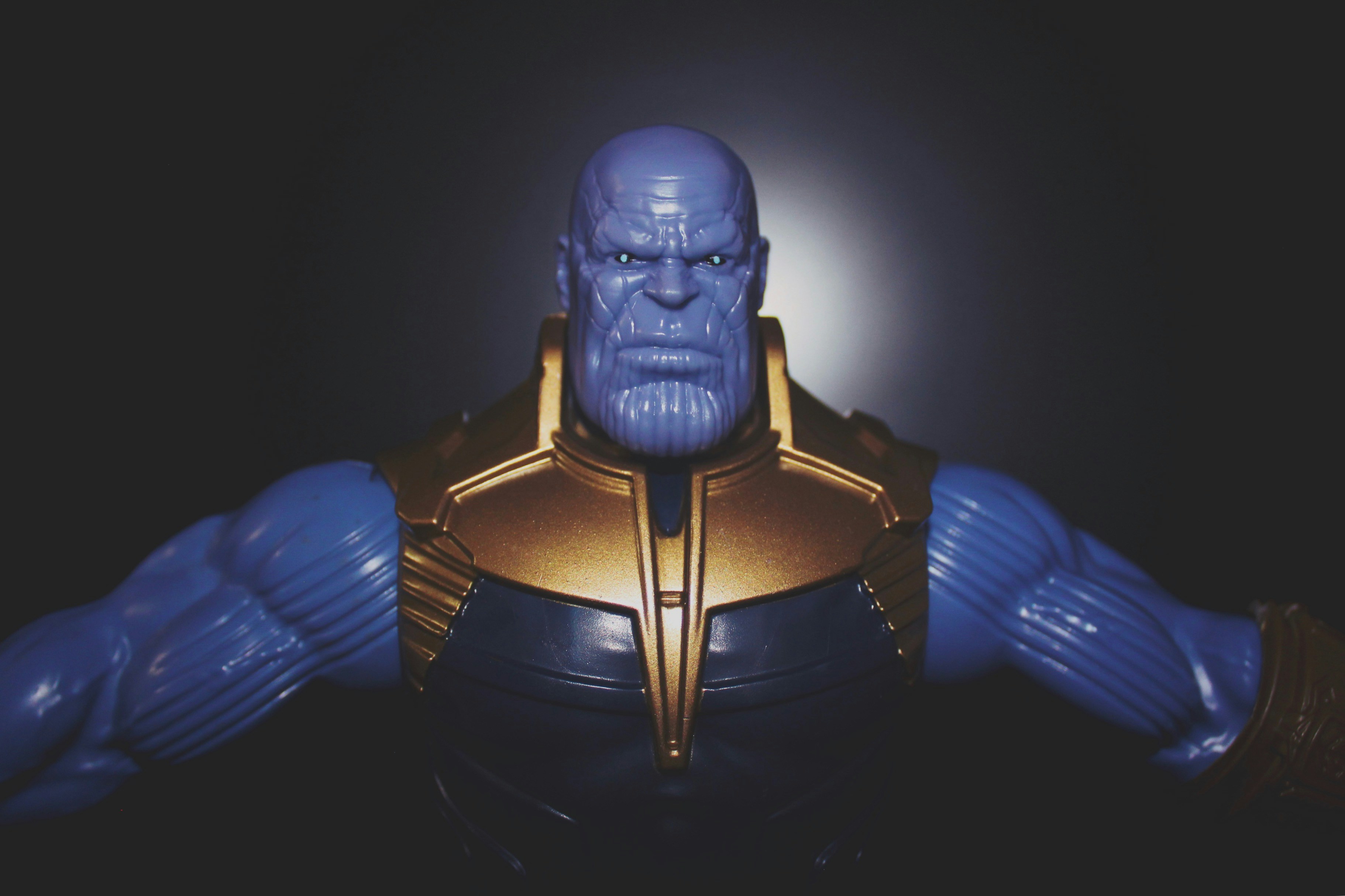 Thanos action figure in battle damaged armor with determined expression in dark cinematic display