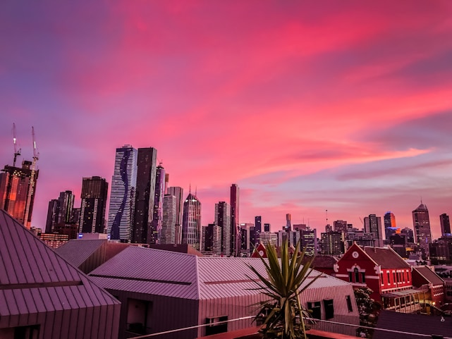 A sleek, modern city skyline at sunset with diverse homes in the foreground.