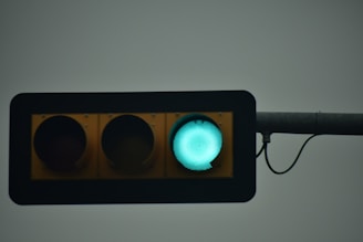 A traffic light is prominently displayed against a gray background, showing a green light lit, while the red and yellow lights are off.