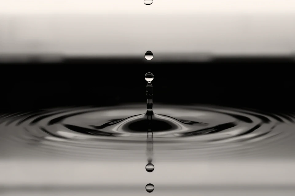 Single drop of water suspended in mid-air against black and white background