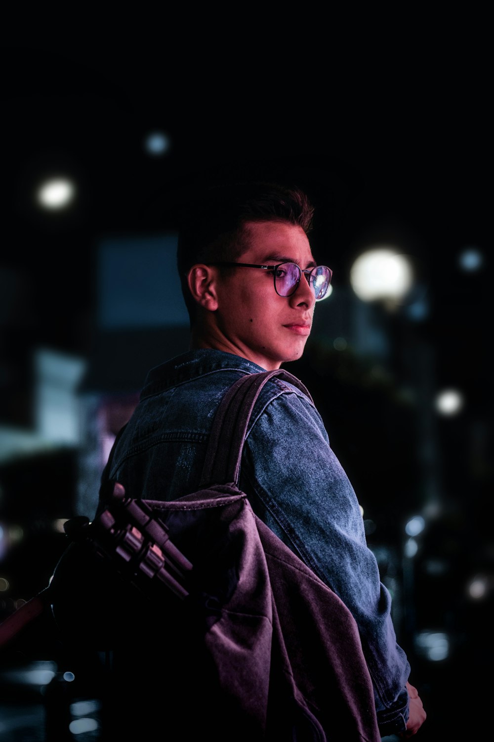 man wearing blue sweater and carrying backpack at night