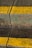 A cracked, weathered concrete surface with moss and two bright yellow lines painted across it. The crack runs vertically through the middle of the image.