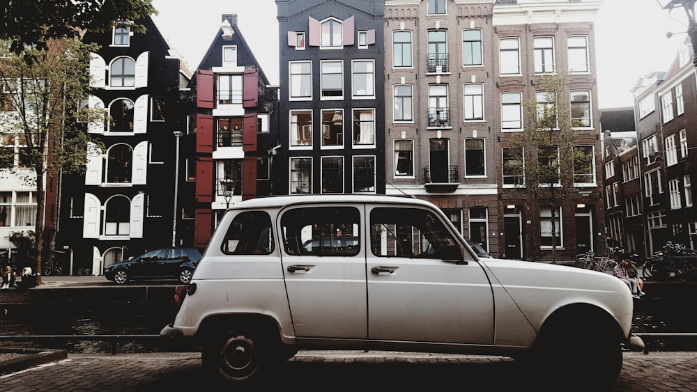 white vehicle parked beside concrete buildings