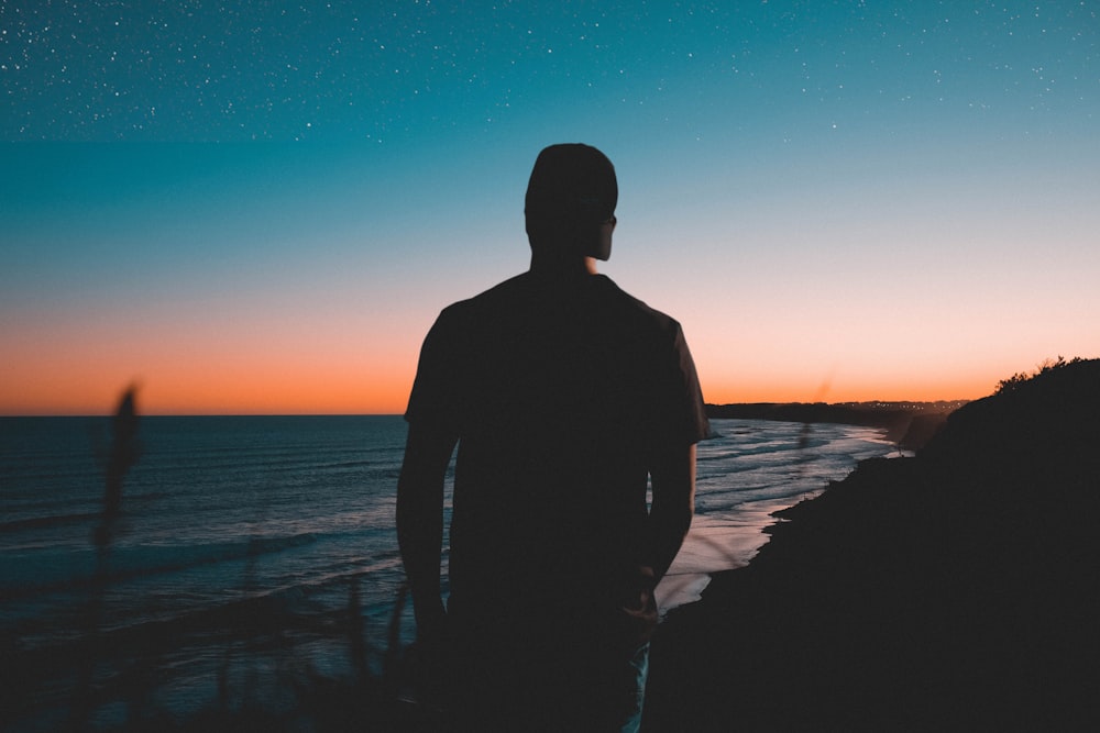 silhouette of man near body of water