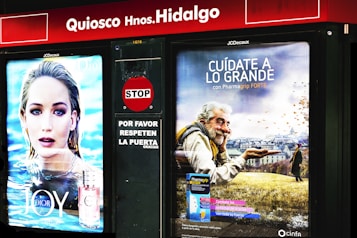 There are two adjoining advertisements at a kiosk. On the left is an advertisement featuring a person with light hair in front of an aquatic background, promoting a perfume called 'JOY by Dior.' On the right is an advertisement depicting an elderly man with a warm smile holding a wooden bowl against a backdrop of a field with autumn leaves, promoting Pharmagrip Forte.