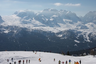 An instructor guiding a group on snowy mountain slopes with clear skies