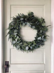 An adjustable length wreath hanger mounted on a front door.