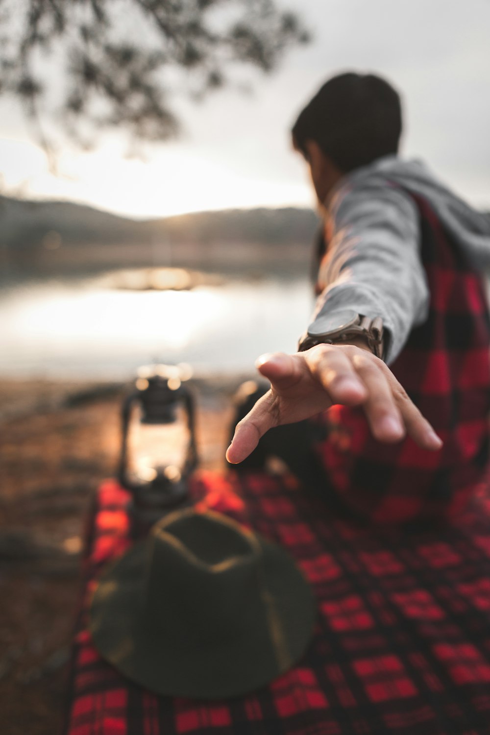 selective focus photo of man sitting in front of body of water