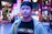 A vibrant neon-lit street scene with a stylish person wearing bold Neonvibe streetwear.