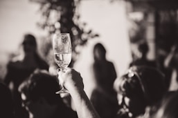photographie en noir et blanc d'une main qui tient un verre de champagne