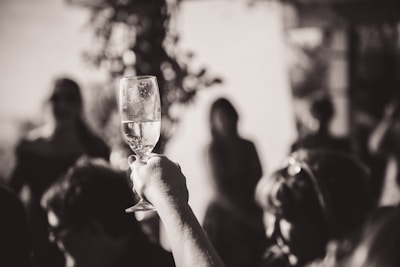 photographie en noir et blanc d'une main qui tient un verre de champagne