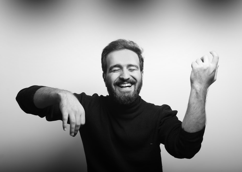 grayscale photography of man raising his hands