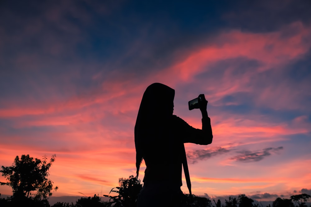 silhouette of woman using smartphone during golden hour