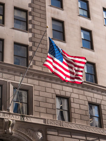 An American flag gently waving outside a corporate building, symbolizing patriotism and commitment.