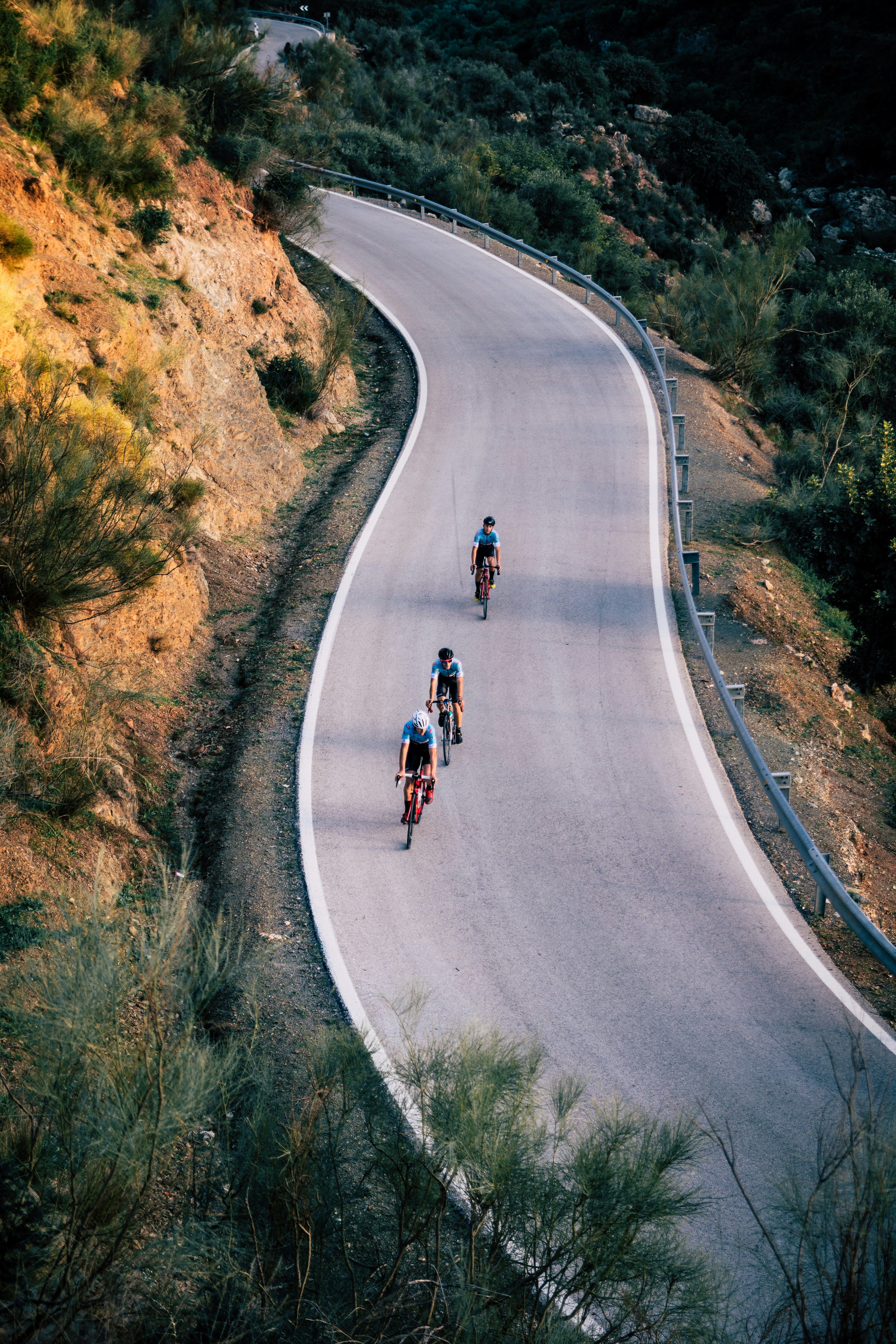 three person riding on bicycles crossing road during daytime