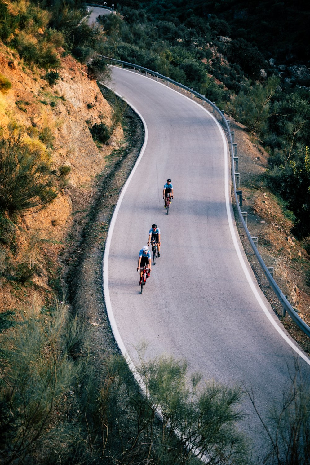 three person riding on bicycles crossing road during daytime