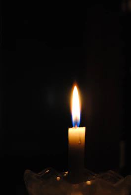 A solitary candle flickering in the dark, embodying the enduring human spirit.