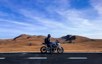 man riding motorcycle at vast land during daytime