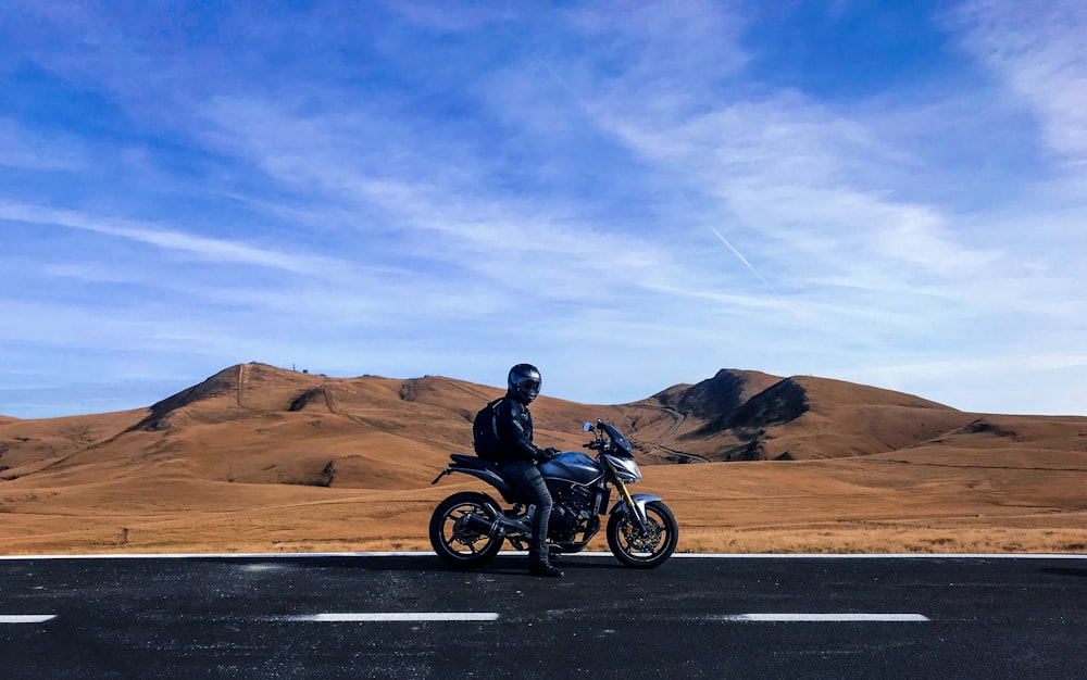 man riding motorcycle at vast land during daytime