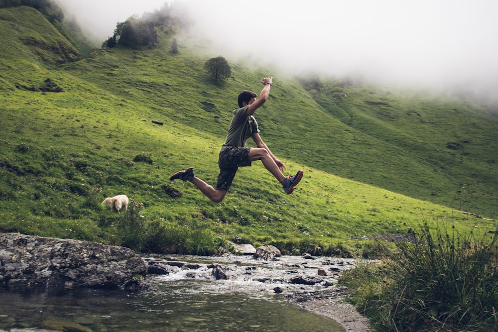 man jumping over body of water during daytime