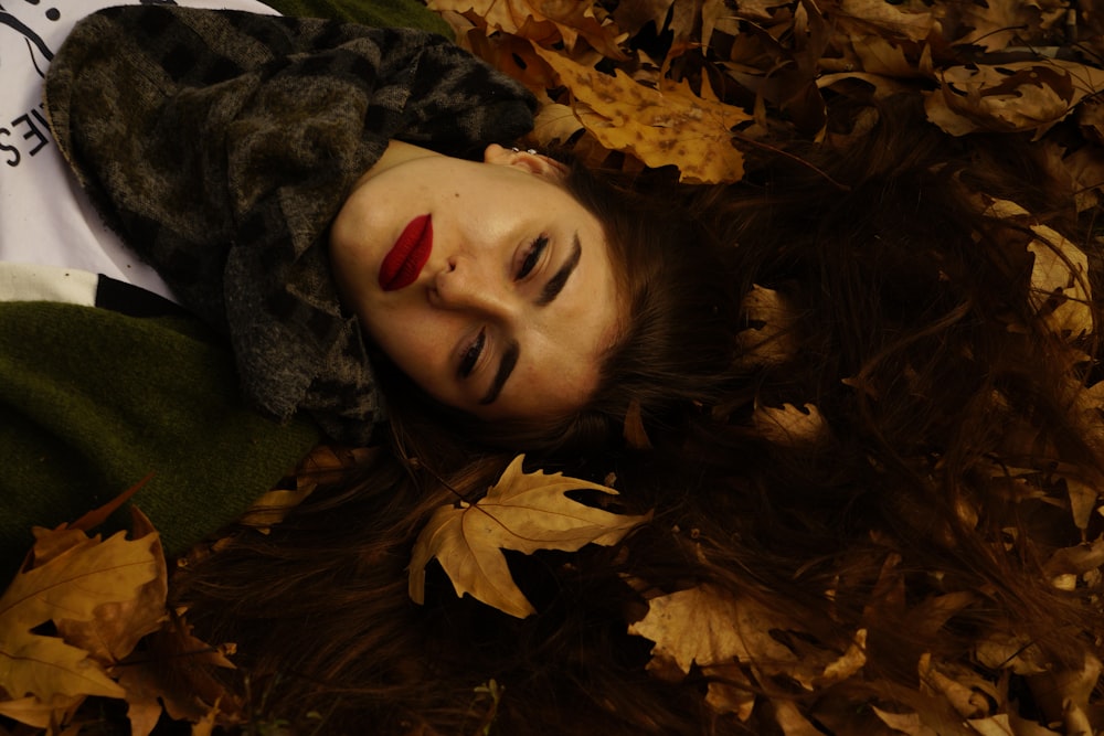 woman lying on brown dry leaves