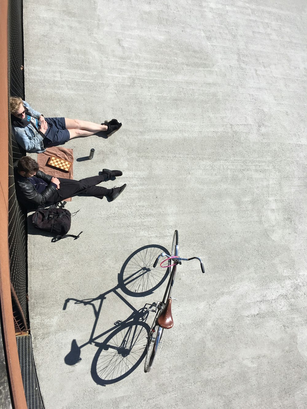 2 personas sentadas en la acera al lado de la bicicleta estacionada durante el día