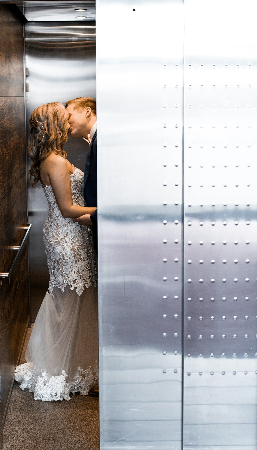 wedding couple kissing behind wall