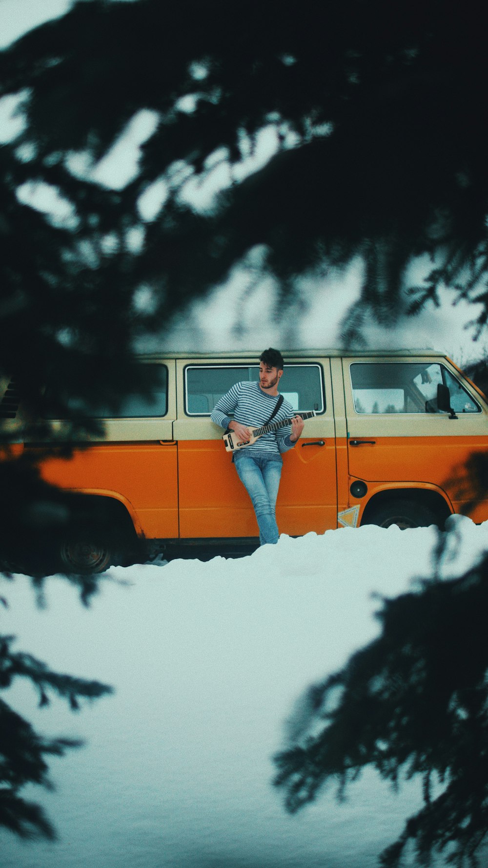 man in sweater standing beside orange car