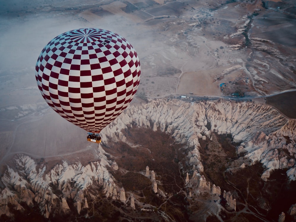 Heißluftballon, der tagsüber über bergigem Gelände schwebt