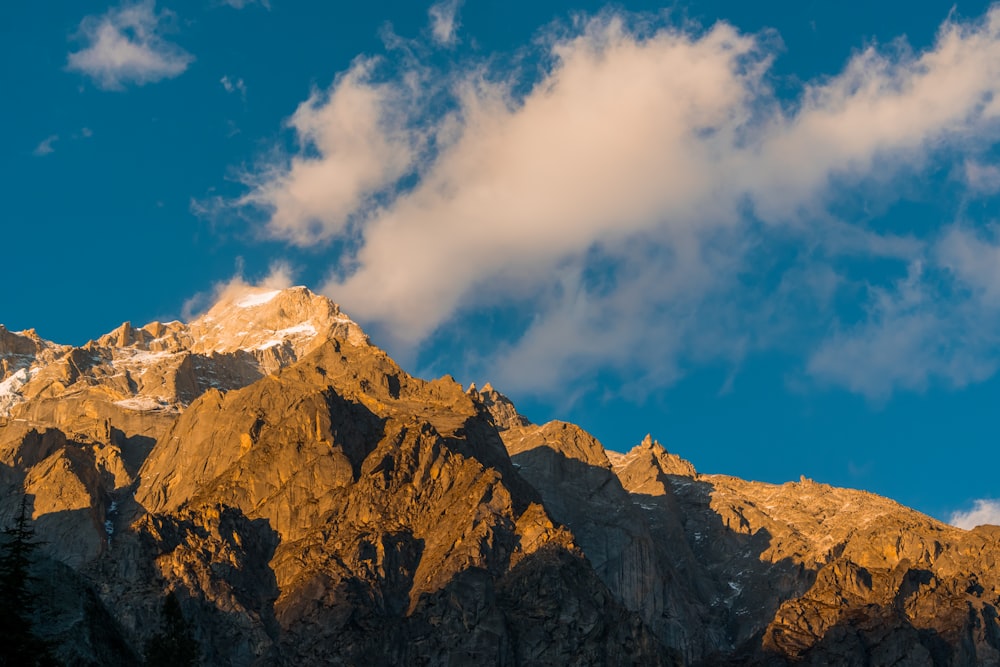 brown rocky mountain under white and blue cloudy sky