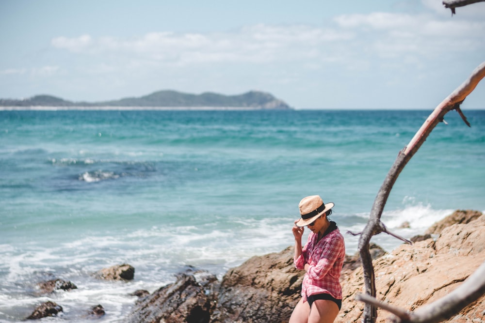 woman standing on rock beside ocean at daytime