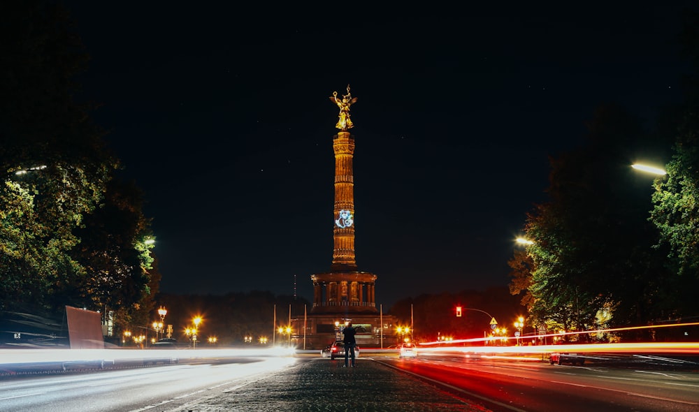 time-lapse photography of vehicle passing on road beside tower