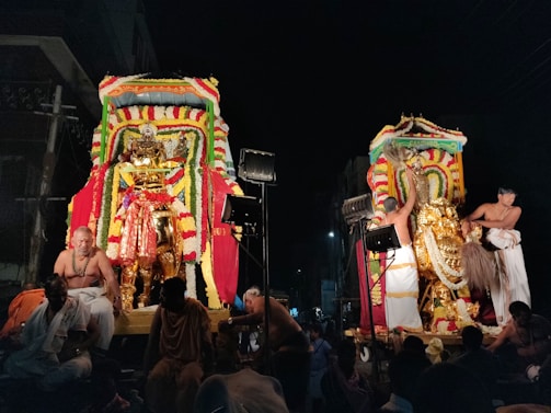 A baraat procession with luxury cars lined up, decorated with vibrant royal red flowers and festive lights.