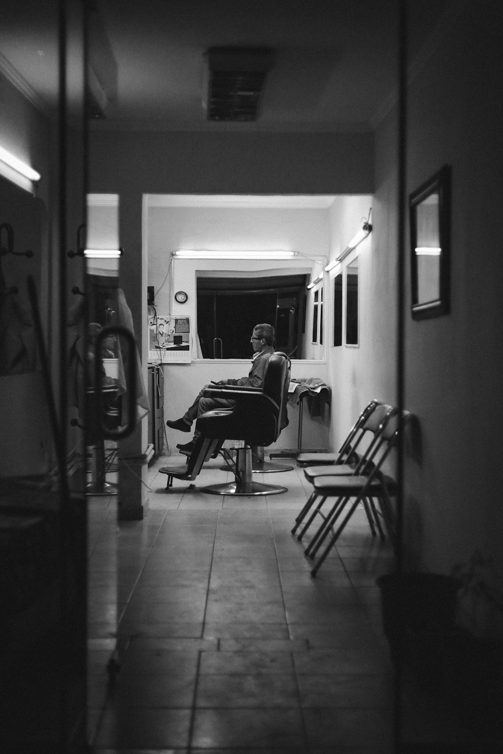 grayscale photo of man sitting on chair