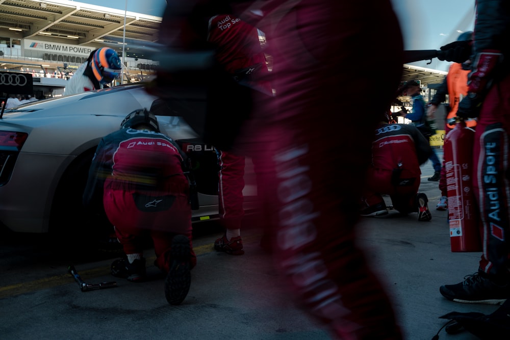 personnes changeant le pneu de l’Audi R8 argentée dans les stands