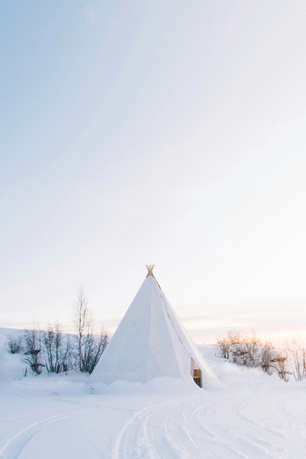 white tipi tent covered with snow