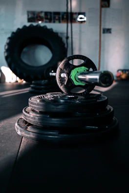 Wide shot of the weightlifting area featuring barbells and benches under moody lighting.