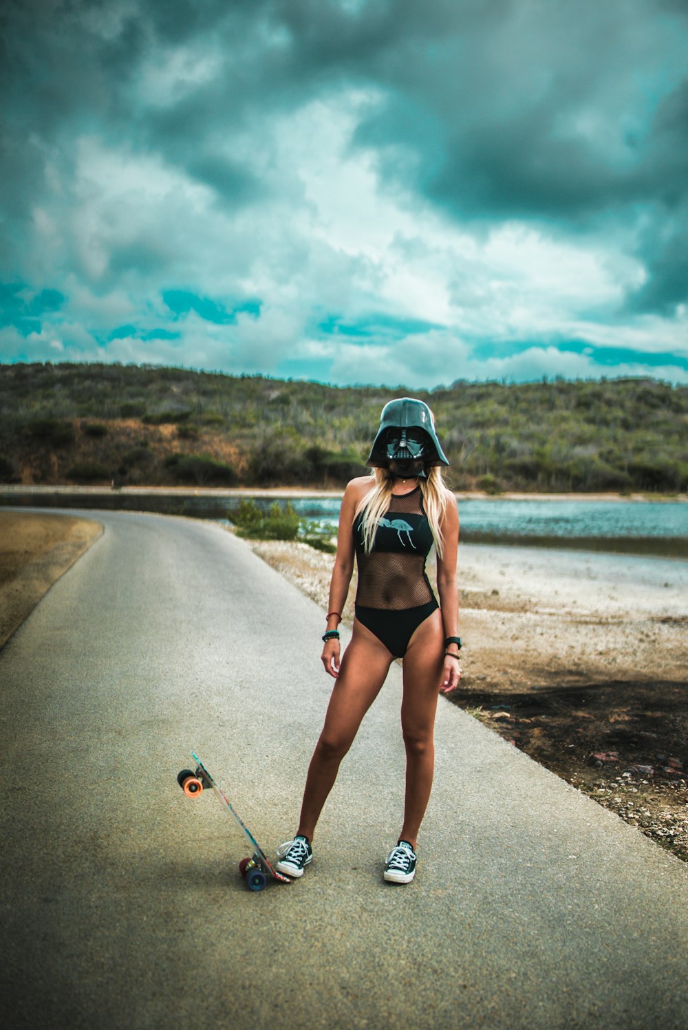 Mujer en monokini negro escalonando la tabla del crucero en la carretera