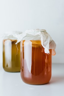 two mason jars filled with liquid on white surface
