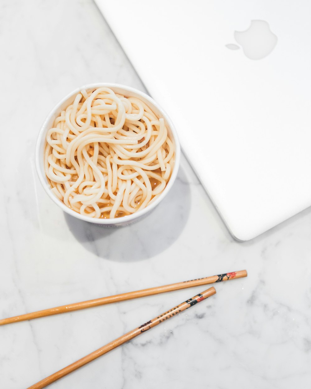 white noodles in bowl beside chopsticks