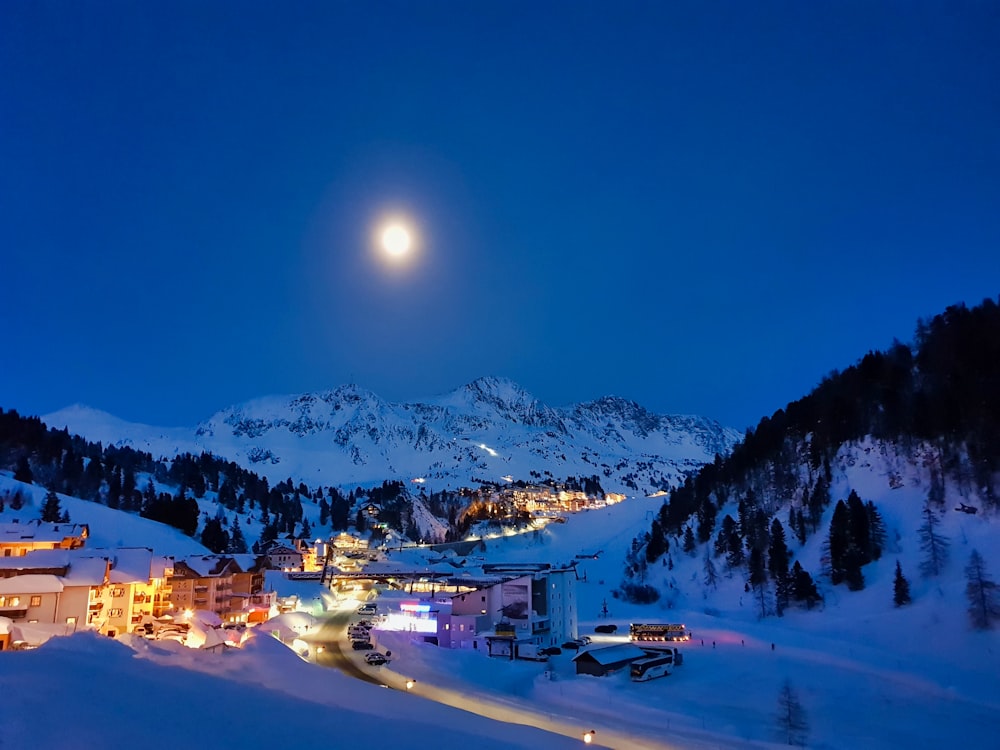 lighted buildings and houses with snow covered field during night time