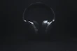 Smartphones and headphones displayed on a minimalist black surface with soft lighting