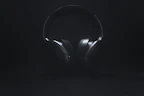 Smartphones and headphones displayed on a minimalist black surface with soft lighting