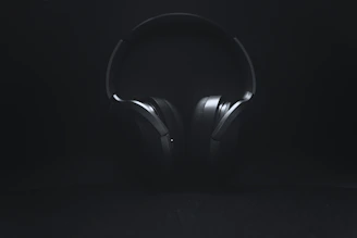 A calm, minimal photo of a vintage pilot’s headset resting on a dark surface with soft yellow lighting.