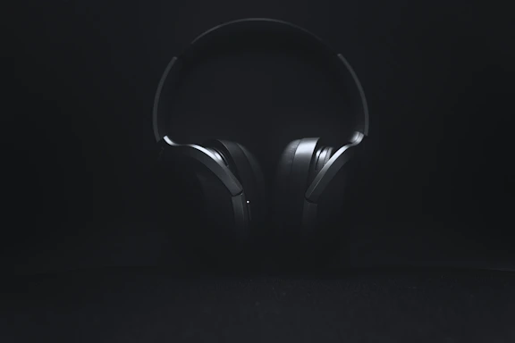 A calm, minimal photo of a vintage pilot’s headset resting on a dark surface with soft yellow lighting.