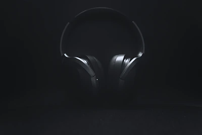 Moody, cinematic shot of headphones resting on a dark surface with neon reflections.