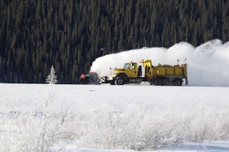 yellow dump truck on snow field during daytime