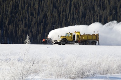 yellow dump truck on snow field during daytime