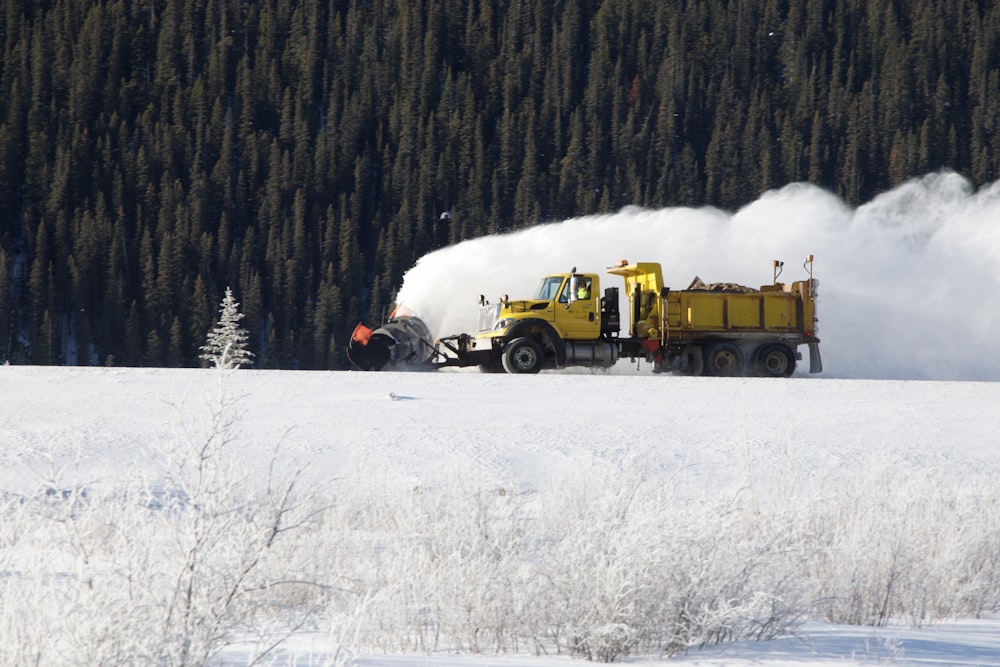 yellow dump truck on snow field during daytime