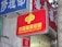A red sign displaying the text 'China Welfare Lottery' in both Chinese and English, mounted on the exterior of a building. The surroundings include a blue sign with Chinese characters and a partial tree trunk visible on the right side.